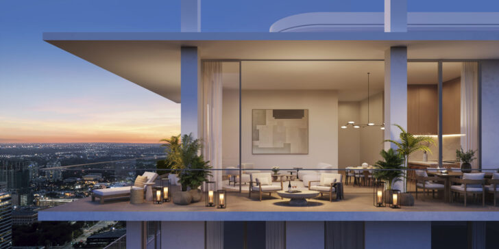 A modern high-rise apartment balcony in Fort Lauderdale at sunset features stylish outdoor seating, potted plants, and lanterns, with an open view of the city skyline. Inside, a dining area and artwork are visible through large glass doors. Lifestyle